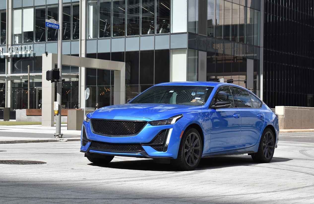 blue sedan parked in front of a large building on a sunny day