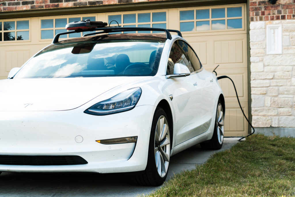 White car parked in a driveway using a home electric charger