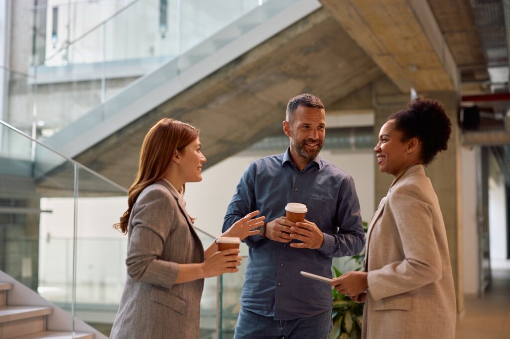 three individuals talking in front of stairs