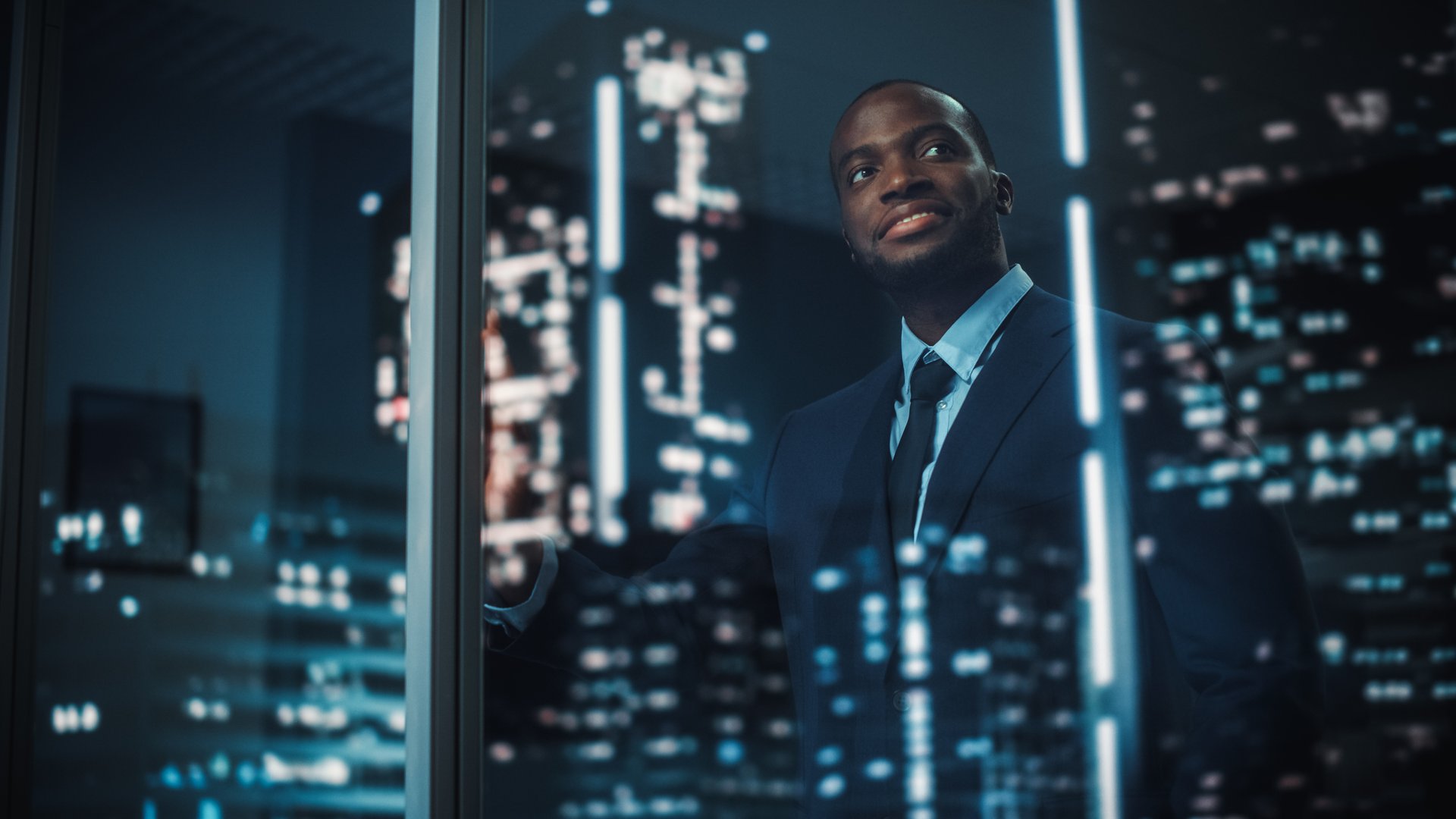 Man looking out window of office building at night