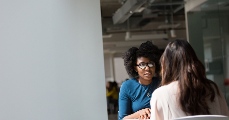 two women sitting at side table talking