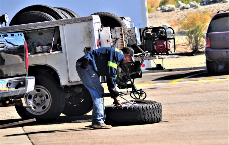 man working on a truck and picking up wheel