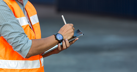 man with orange reflective vest holding tablet