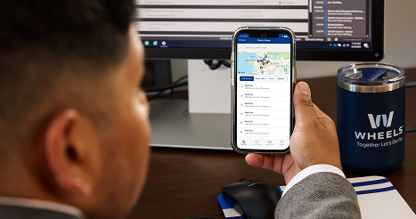 image of wheels employee holding a phone with maintenance shop locations on the screen