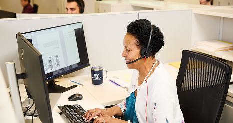 Wheels employee working on computer at desk with headset on