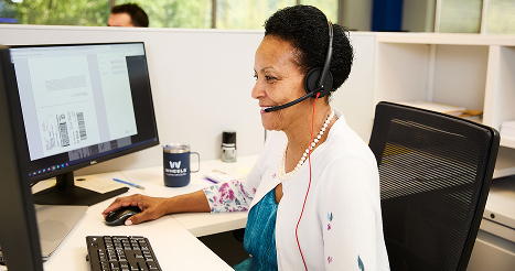 Wheels female employee working on a computer and wearing a headset
