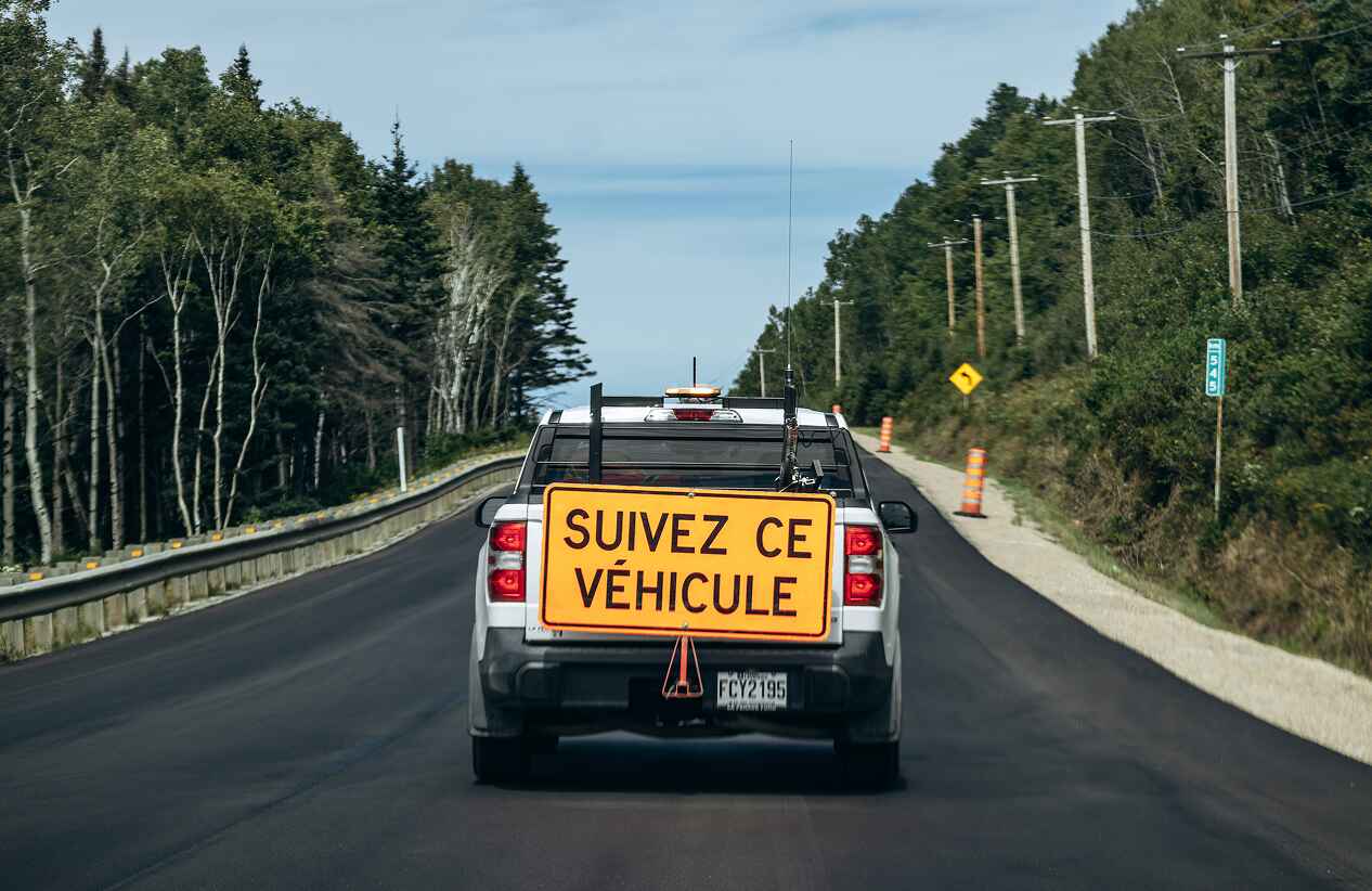 truck with construction warning sign driving down road in Canada